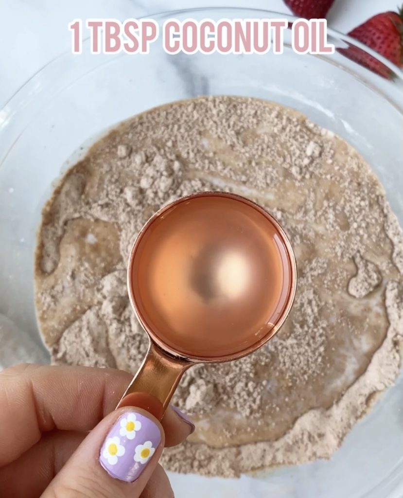 melted coconut oil in a measuring cup over a bowl