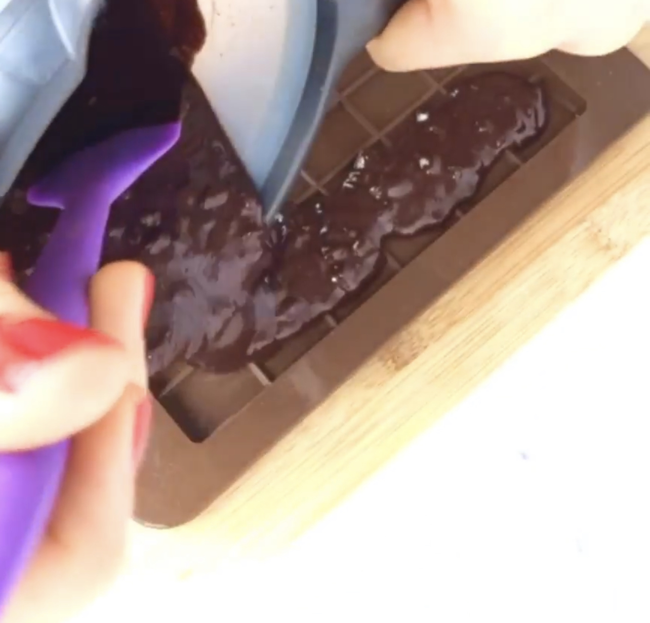 Spreading the melted chocolate into a chocolate mold.