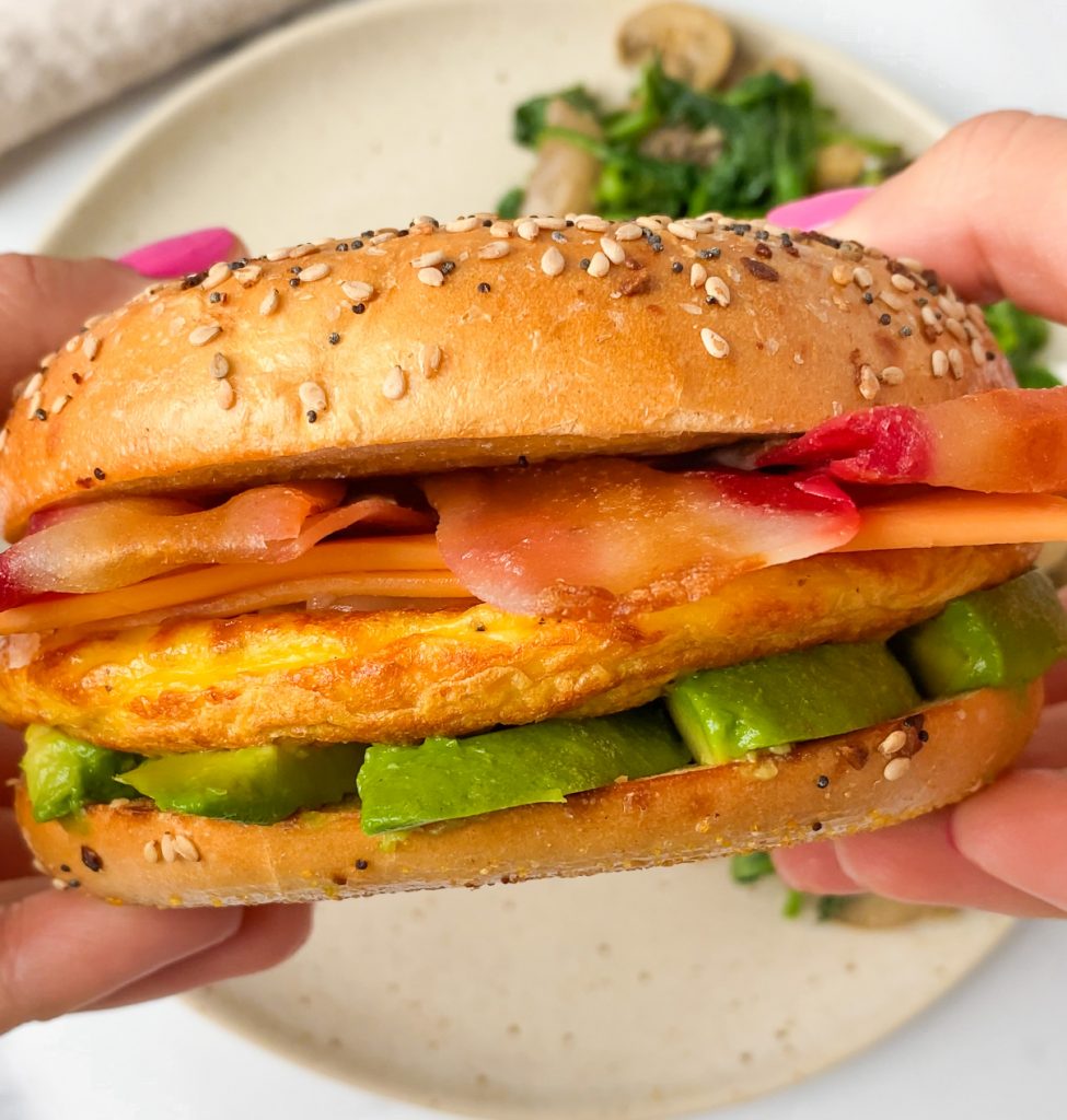 hands holding a vegan breakfast bagel