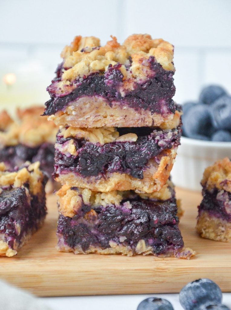 blueberry crumble bars stacked on a board