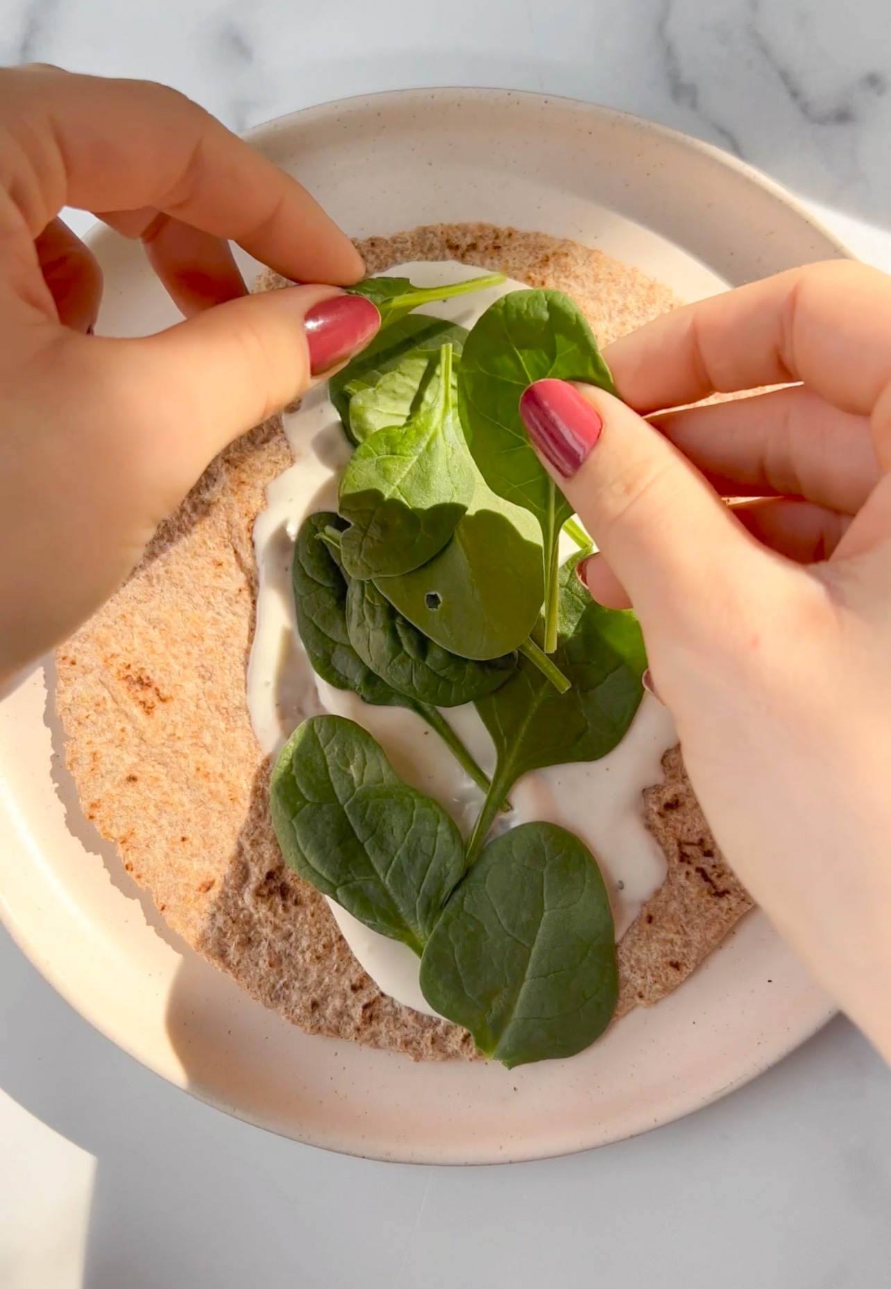 spinach being added to a tortilla