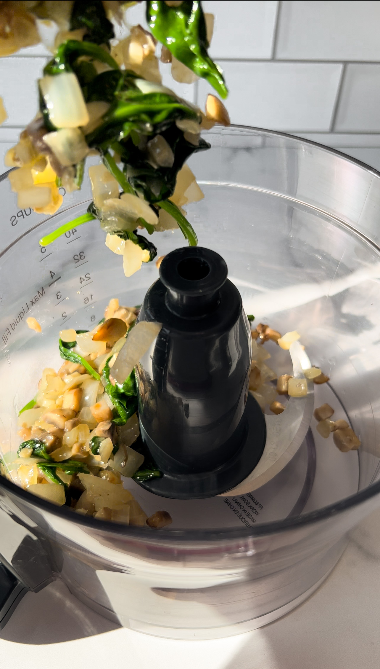 adding sautéed mushrooms, spinach, and onion to a food processor