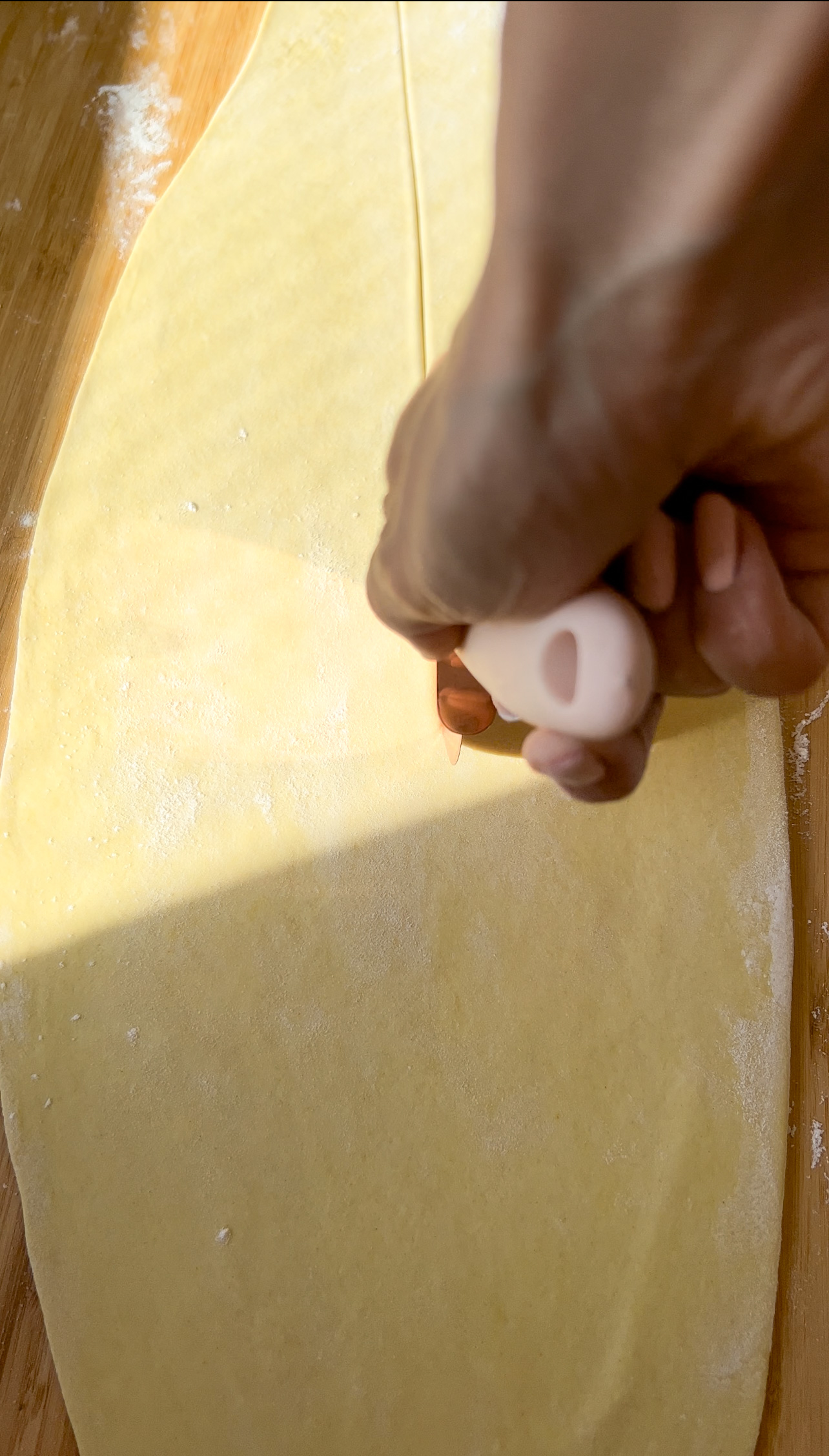 pizza cutter cutting into fresh pasta dough