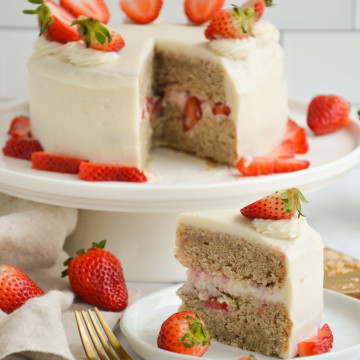 vanilla cake with strawberries on top with a slice on the side