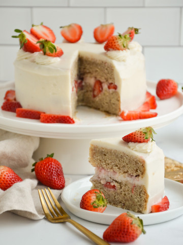 vanilla cake with strawberries on top with a slice on the side