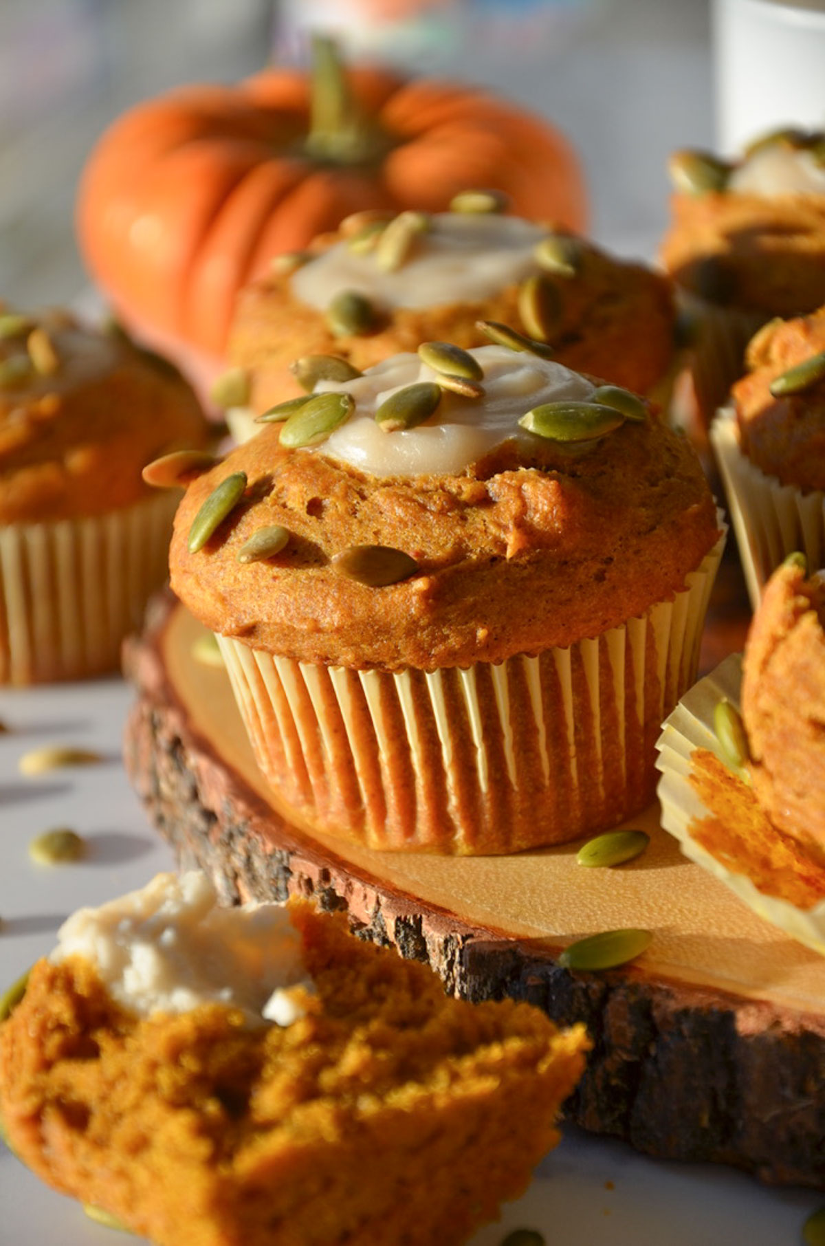 A closeup of pumpkin cream cheese muffin on a tray with a pumpkin in the background.