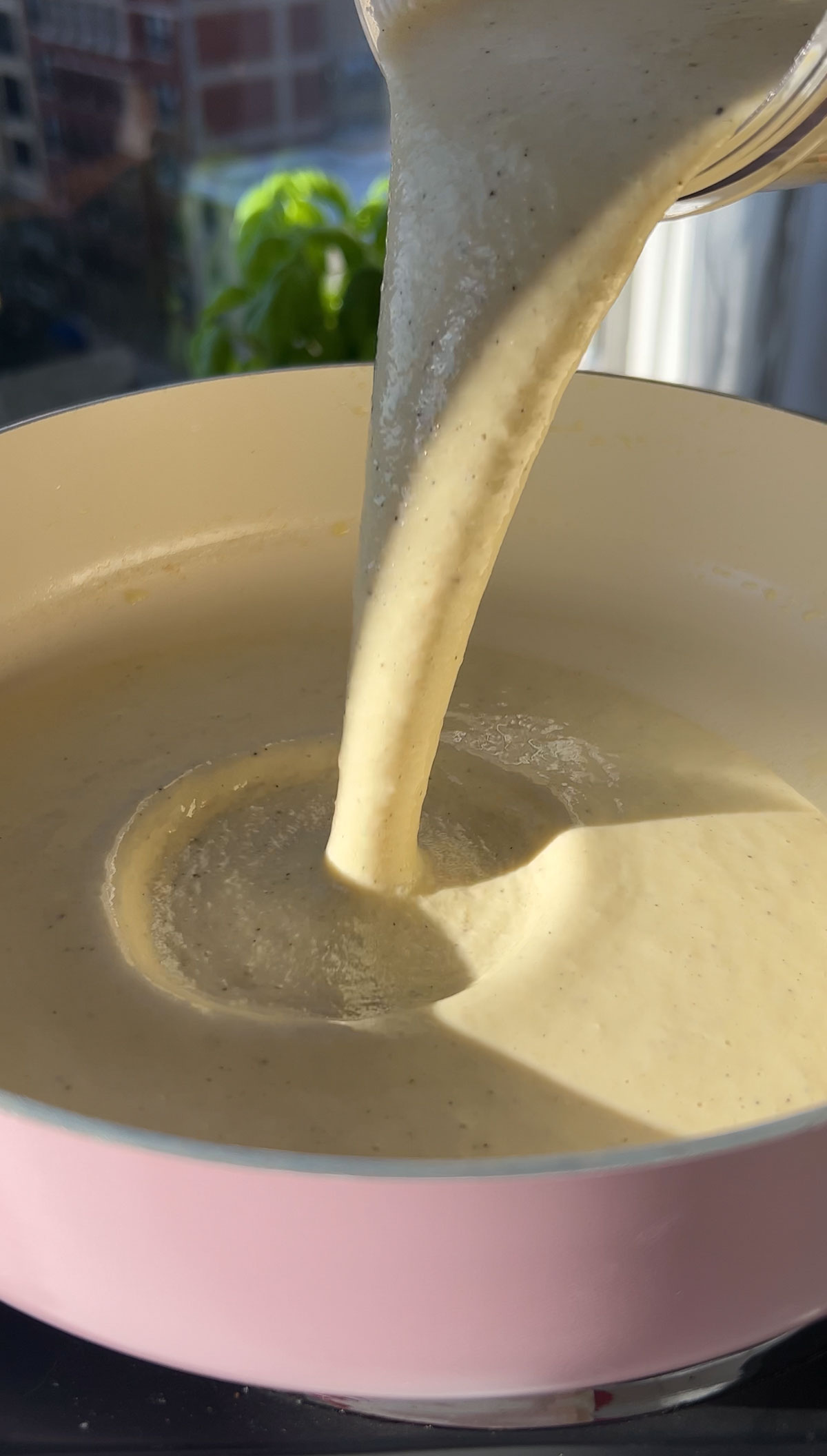 Pouring the vegan alfredo sauce after blending it into a pan.