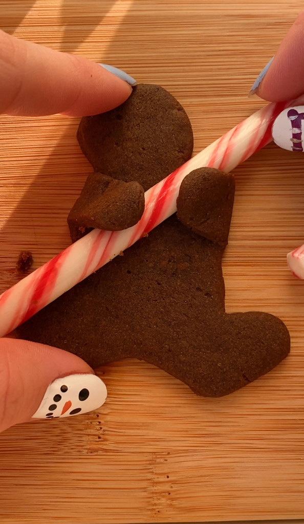 vegan gingerbread cookie holding a candy cane