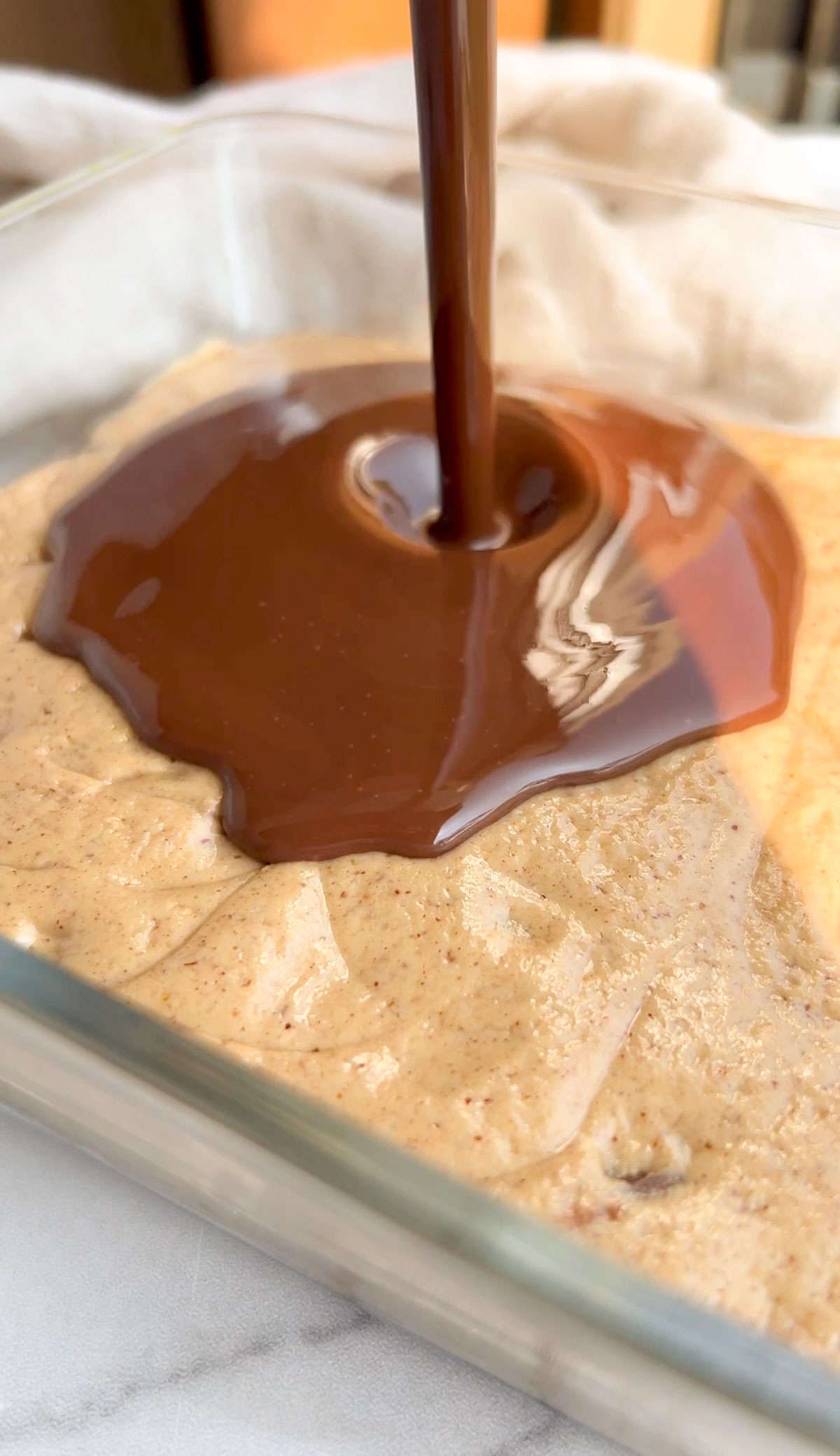 pouring melted chocolate on top of peanut butter bars