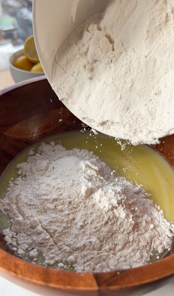 adding flour to a bowl of ingredients