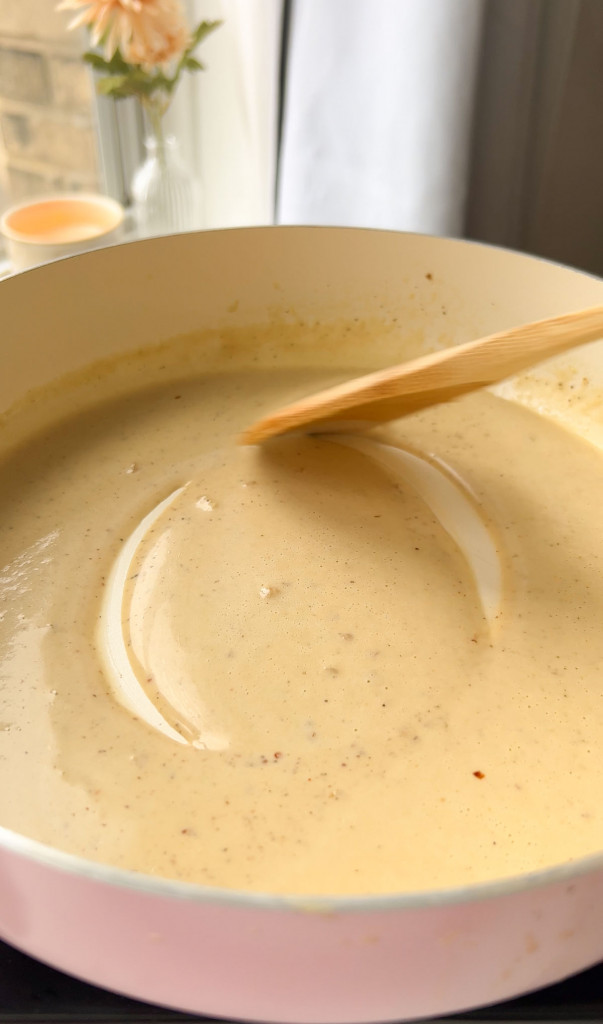 stirring creamy lemon garlic pasta sauce in a pan