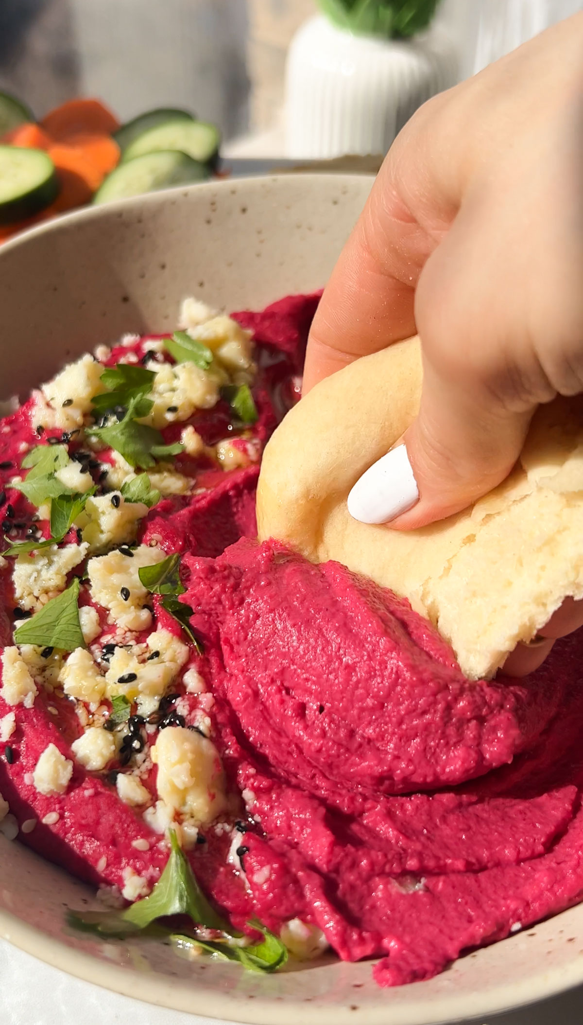dipping naan into a bowl of roasted beet hummus