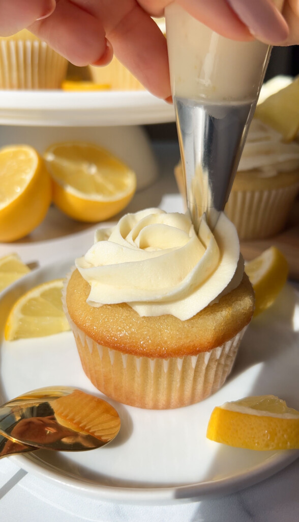 piping icing on top of a vegan lemon cupcake