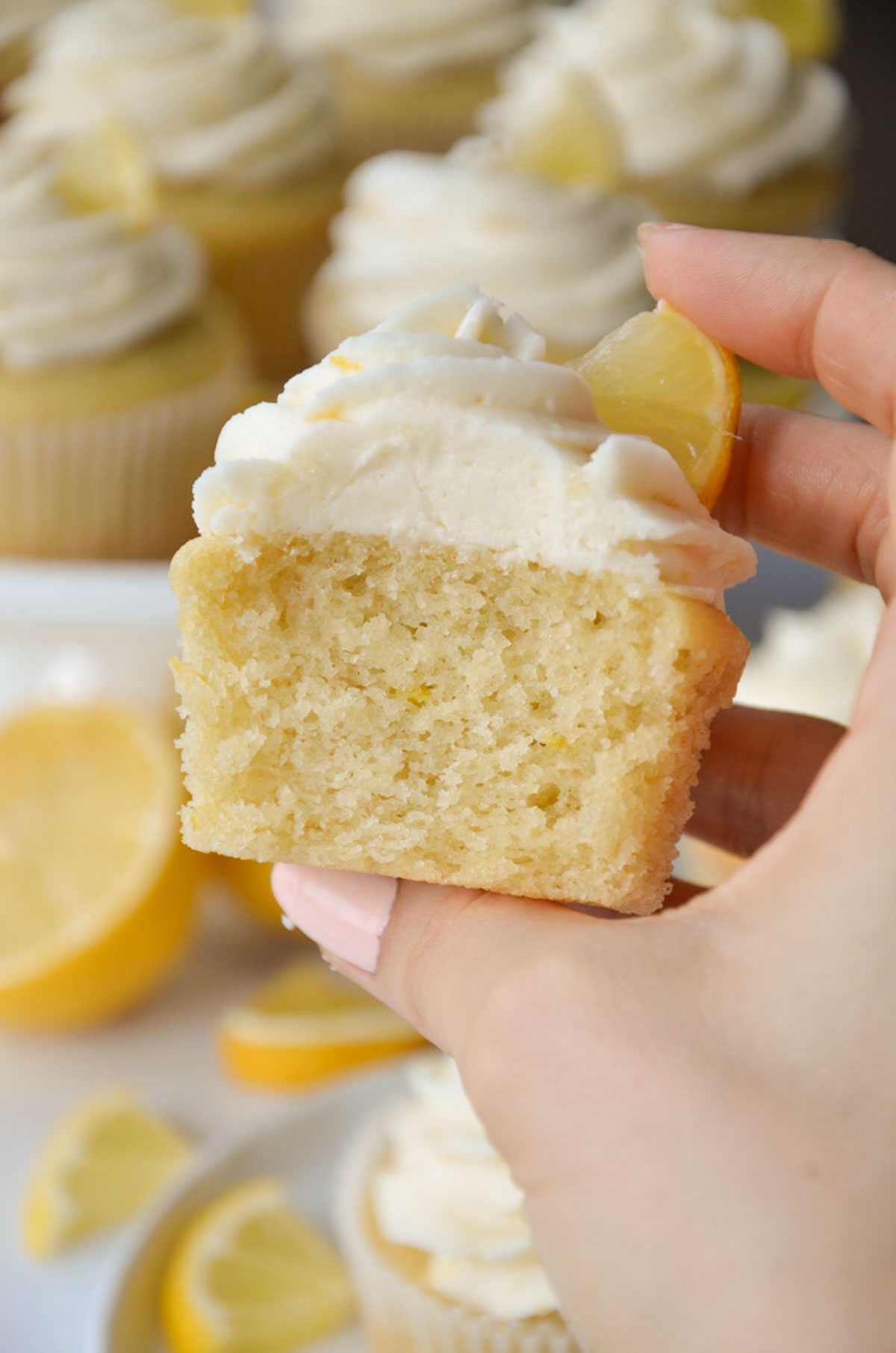 hand holding a vegan lemon cupcake sliced in half