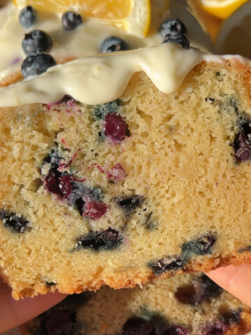 hands holding a slice of vegan blueberry cake