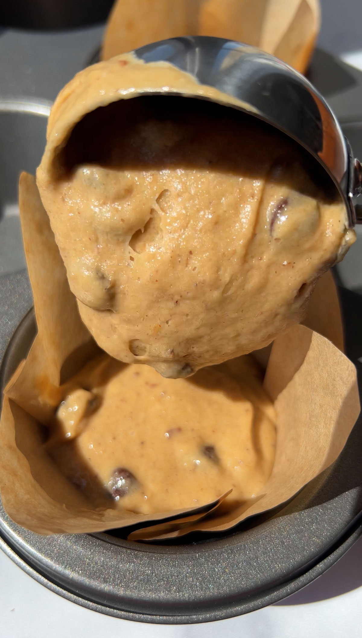 scooping out muffin batter into a muffin cup