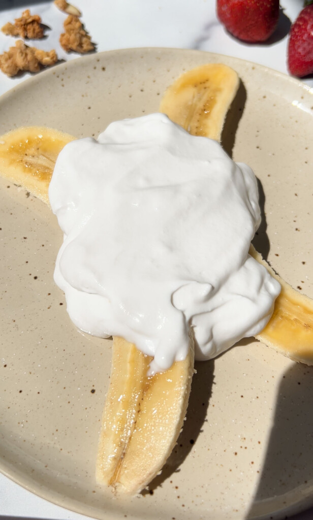 banana split on a plate with yogurt on top