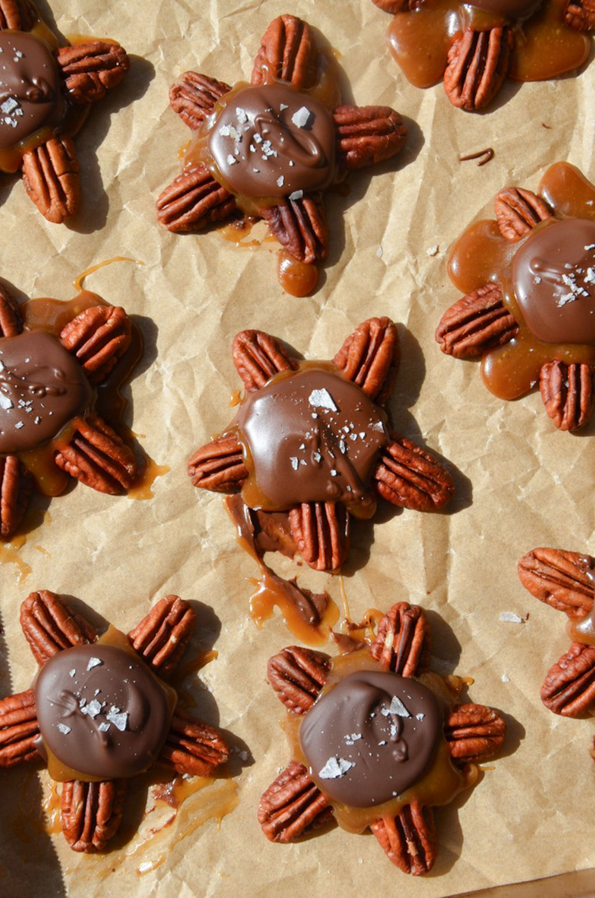 Chocolate pecan turtle clusters on a baking tray.