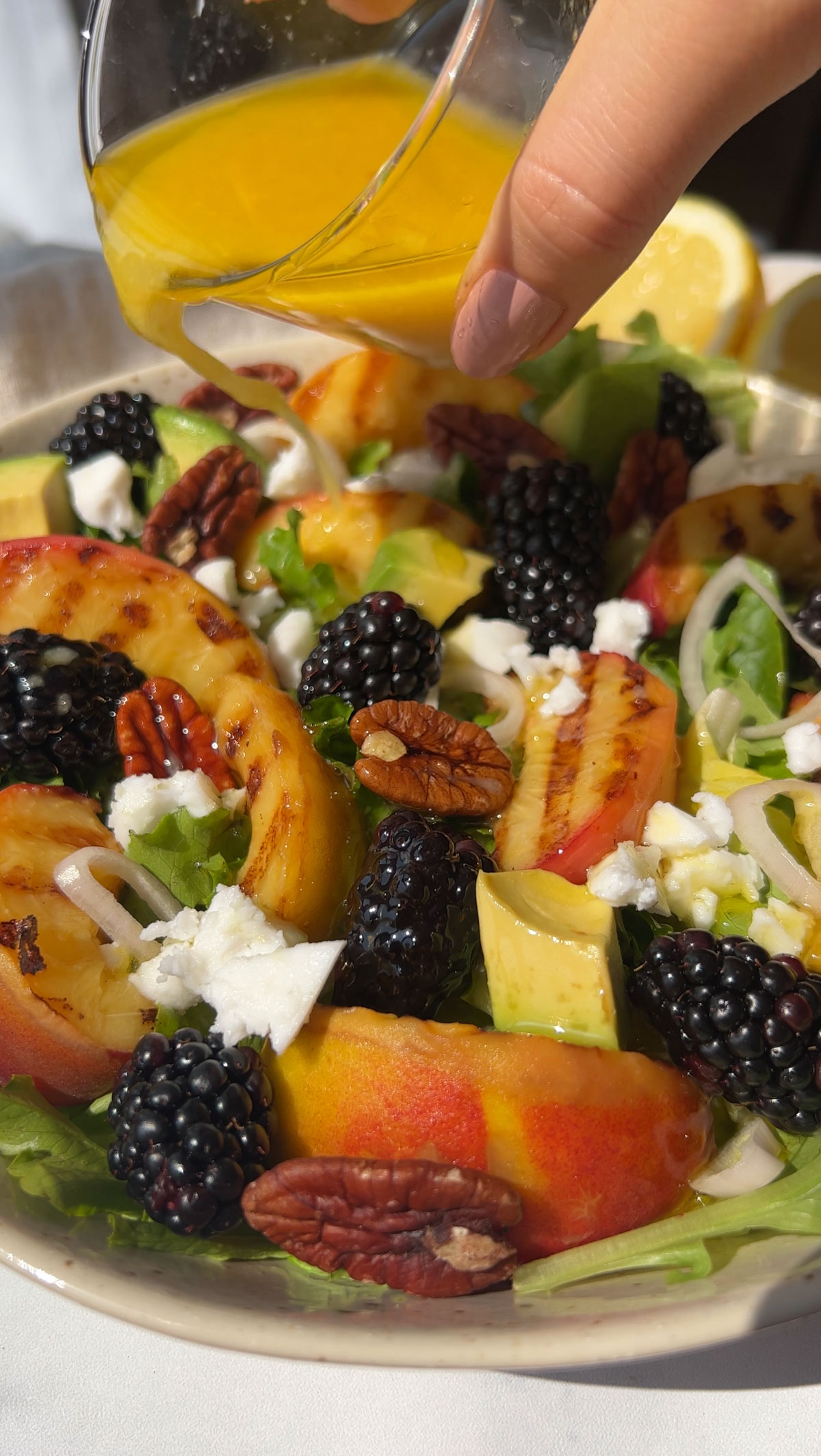 Adding the dressing to the top of a peach salad.