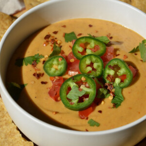A bowl of cashew dip with jalapenos and cilantro on top.