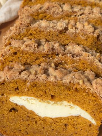 Vegan pumpkin bread with streusel topping sliced on a platter.