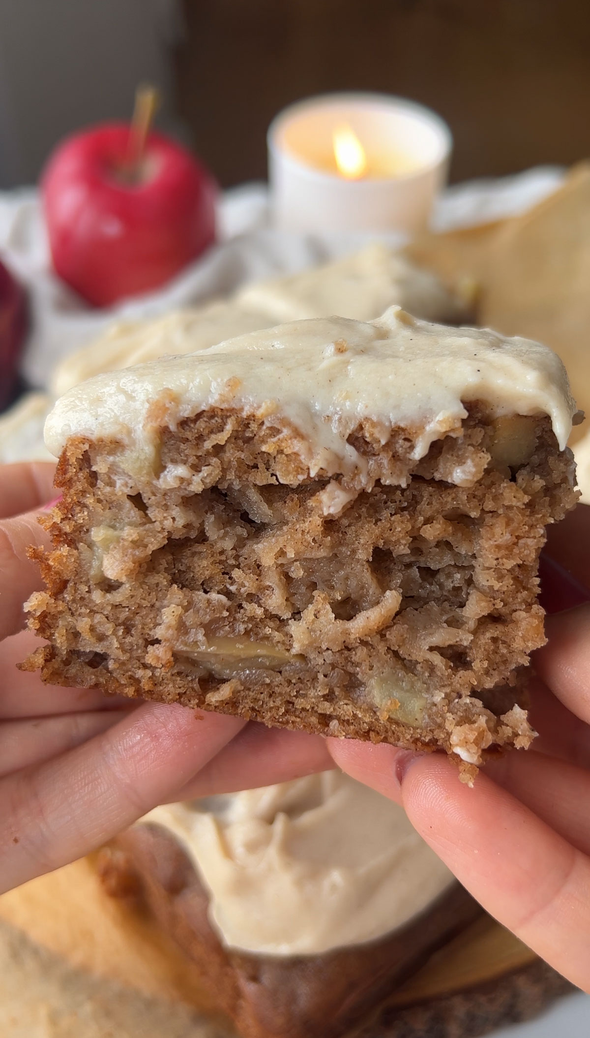 Hands holding up a piece of vegan apple cake.