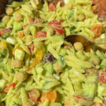 A closeup of vegan orzo salad with a spoon dipping in.