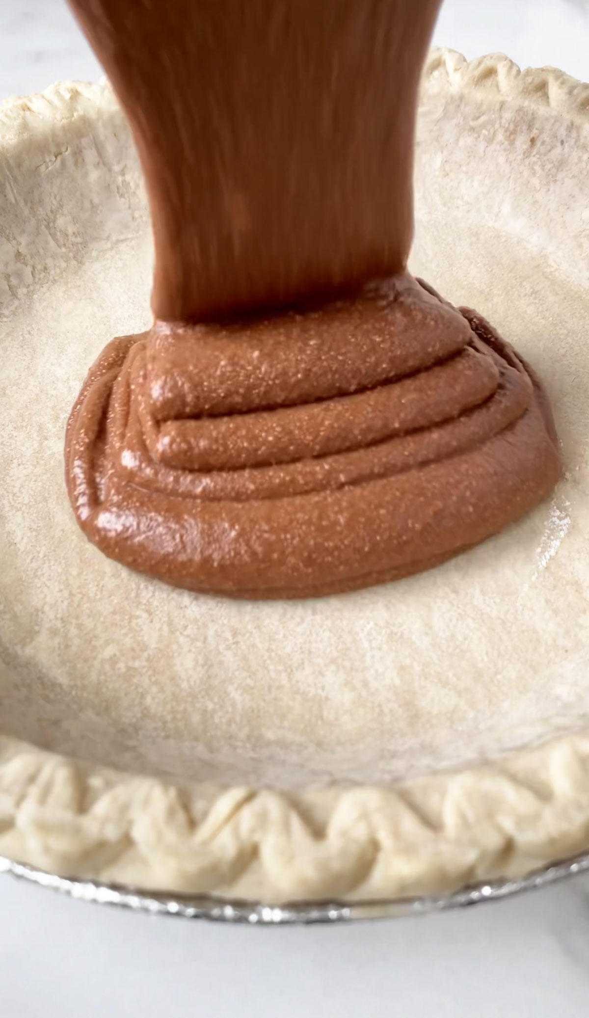 Pouring the vegan chocolate mixture into a pie shell.