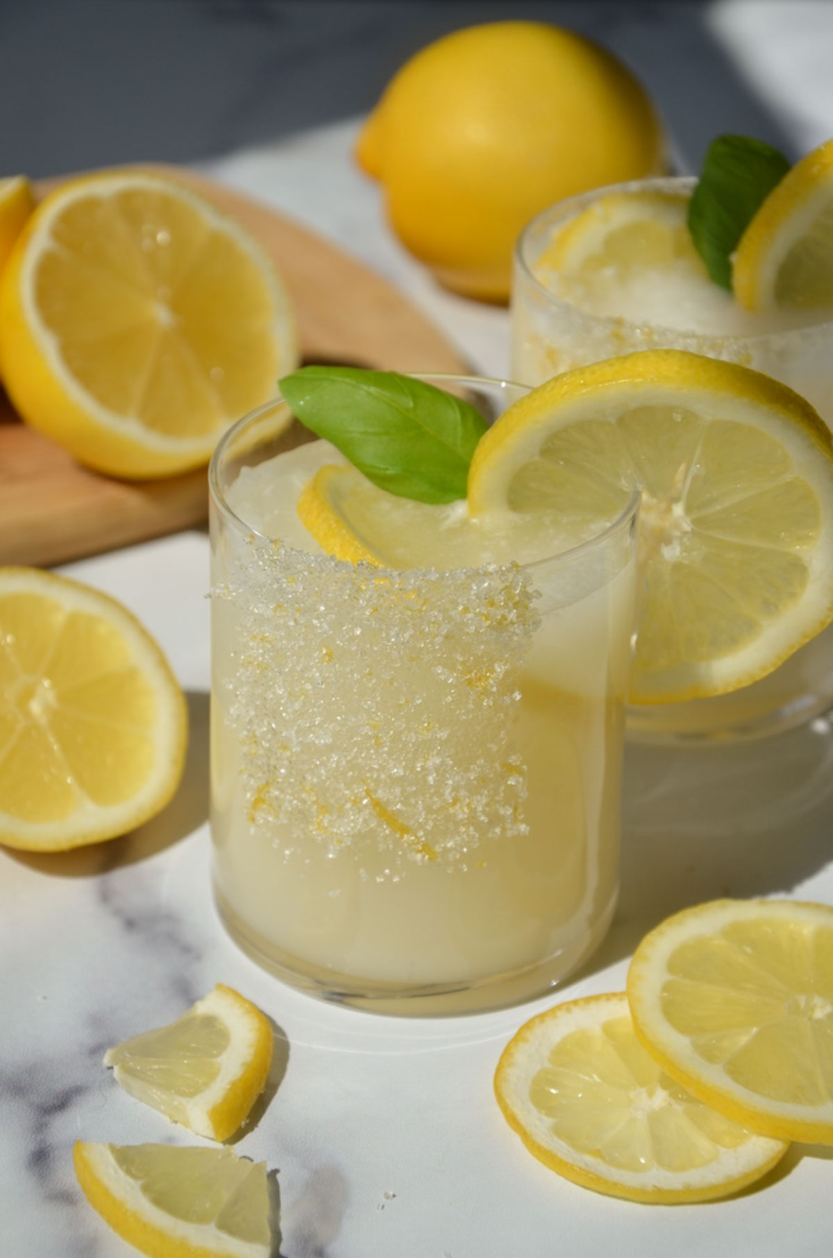A glass of creamy lemonade on the table with a lemon wheel on the rim and around the glass.