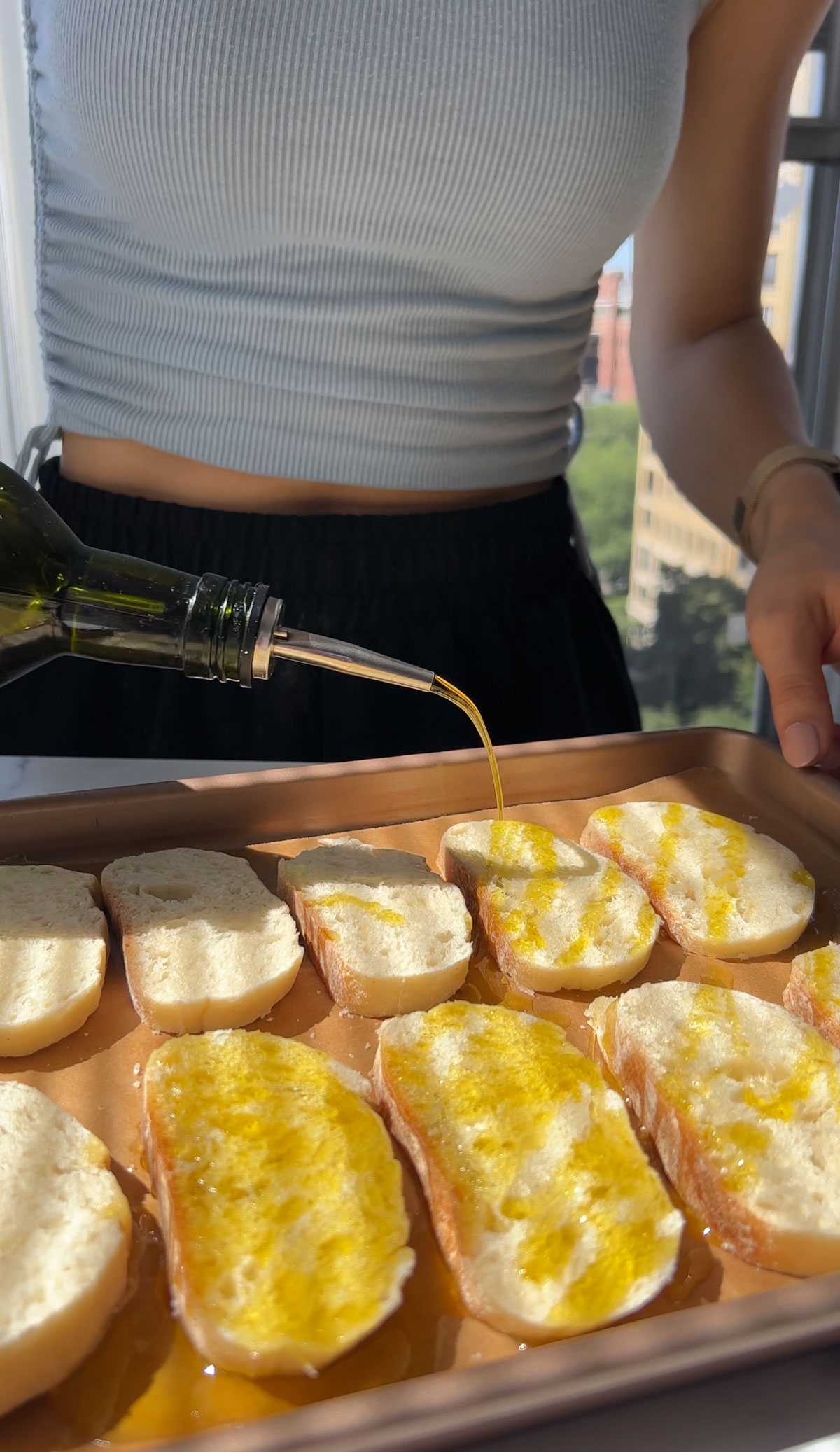 Bread sliced on a baking tray and drizzling with olive oil.