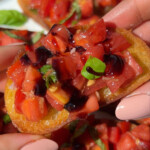 A piece of vegan bruschetta held up with two hands.
