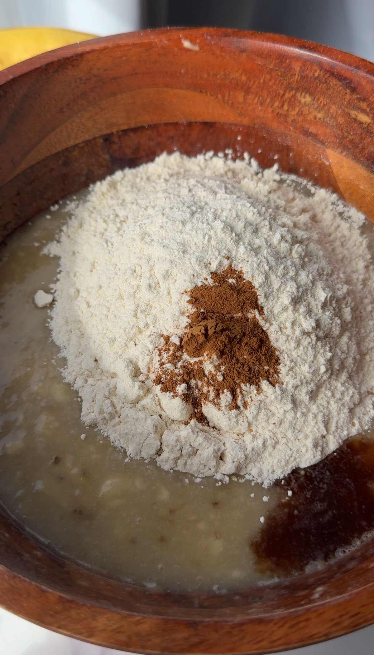 Dry ingredients for vegan banana cake in a brown wooden bowl.