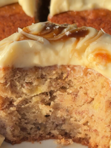 Frosted vegan banana cake portion with a bite missing.