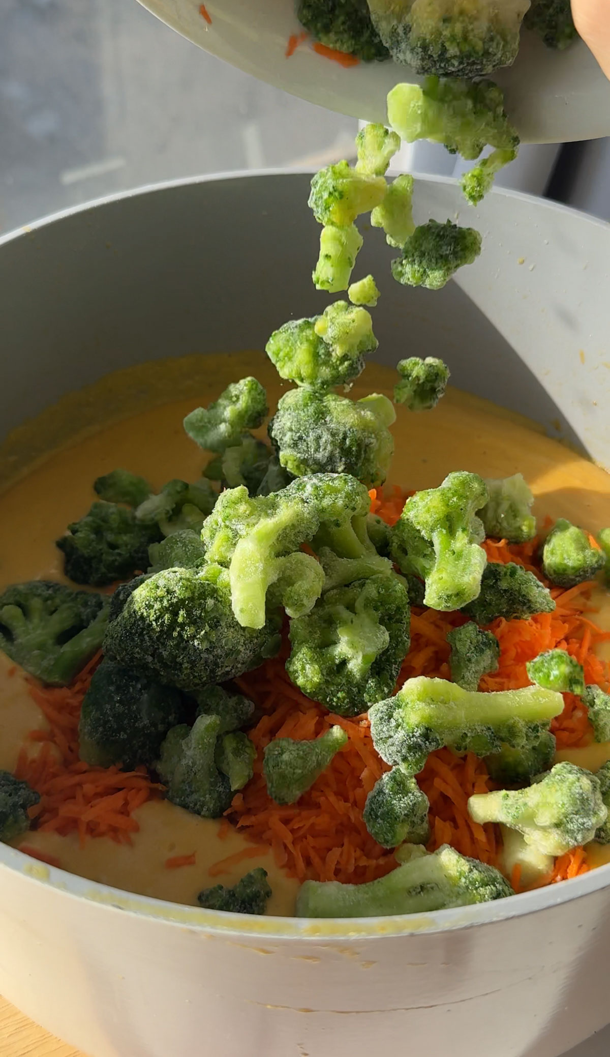 Broccoli florets being added to soup.