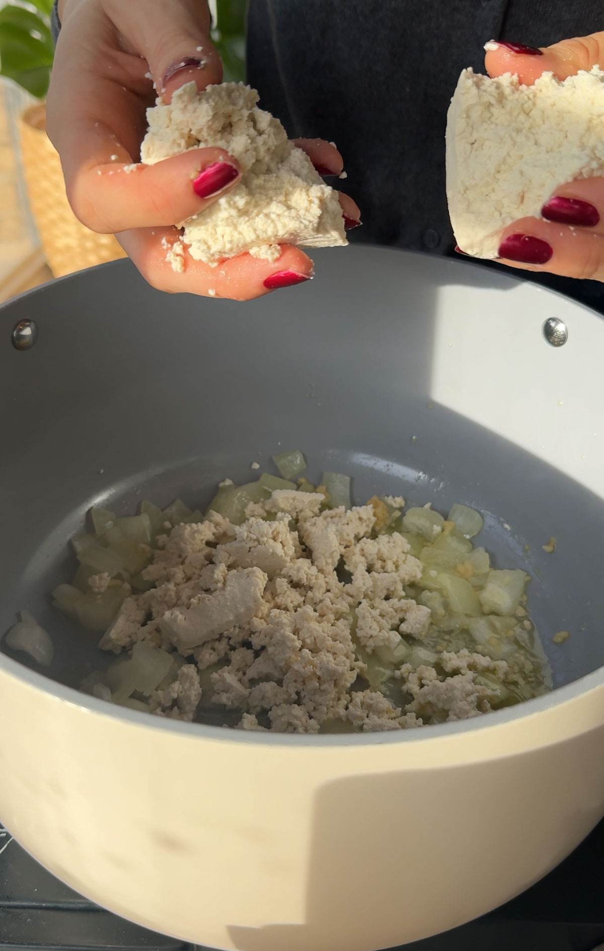 Onions and tofu being sauteed in a pot.