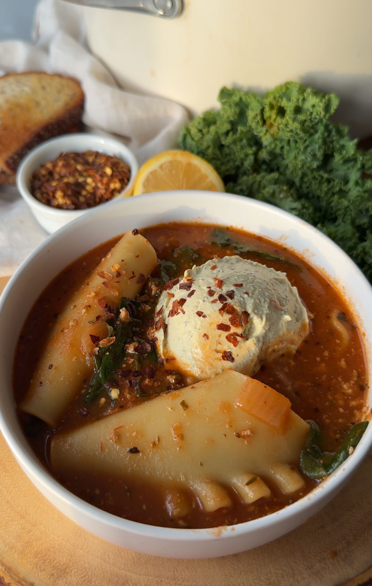 A bowl of vegan lasagna soup sprinkled with crushed red pepper. 