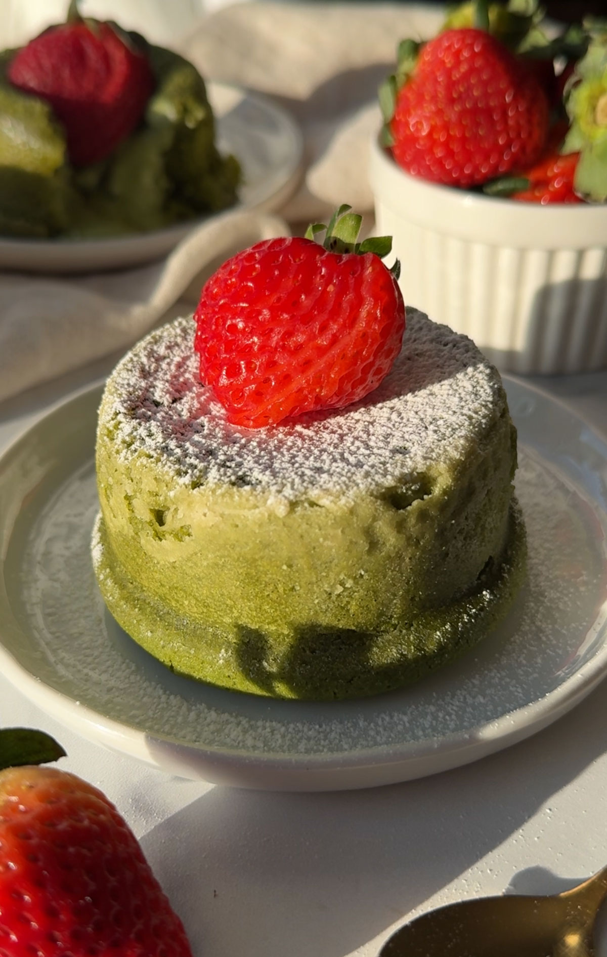 A matcha lava cake topped with a fresh strawberry.
