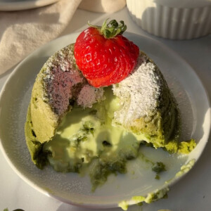 A matcha lava cake on a plate cut so the middle pools out.