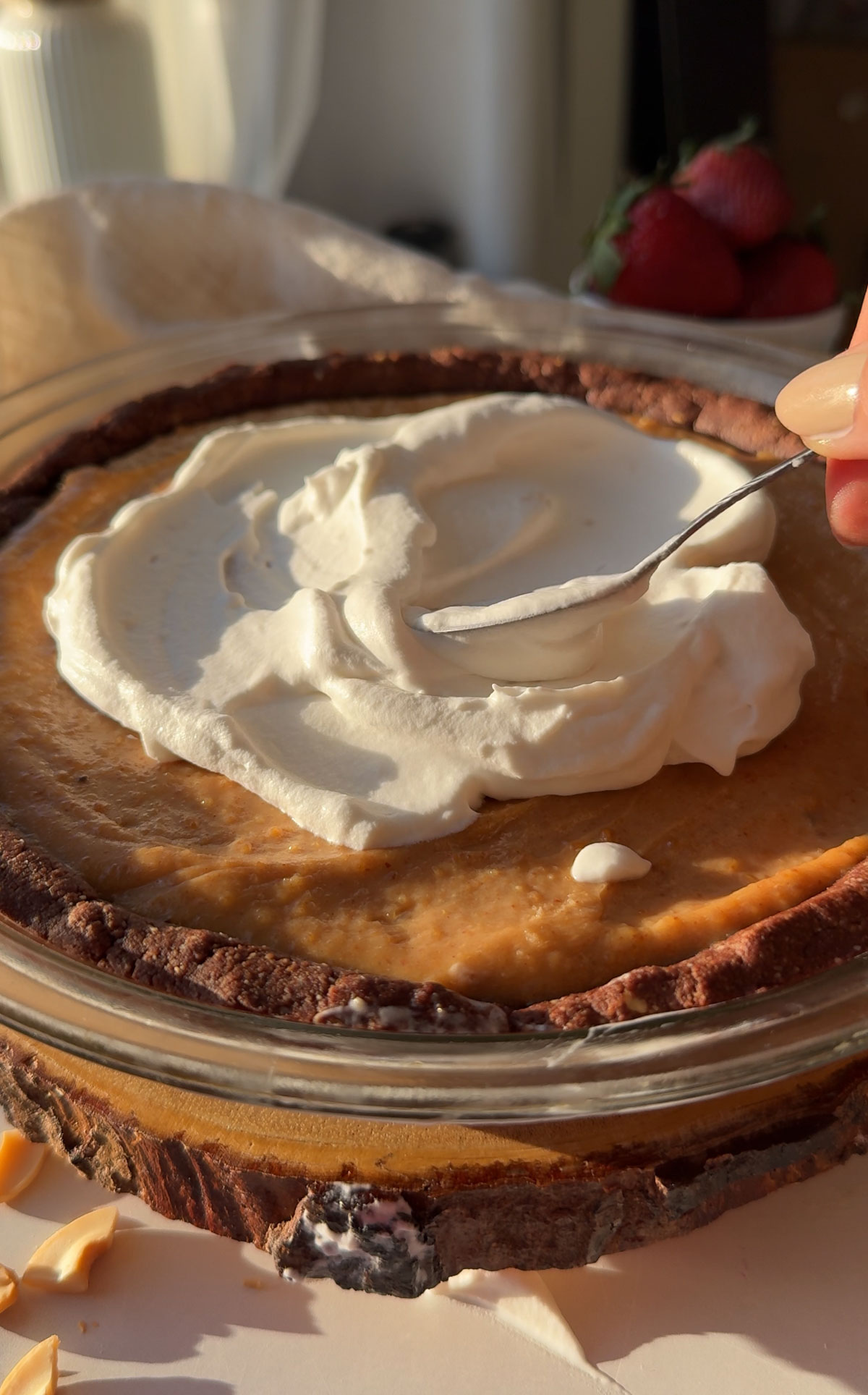 Whipped cream being spread on top of the peanut butter pie.