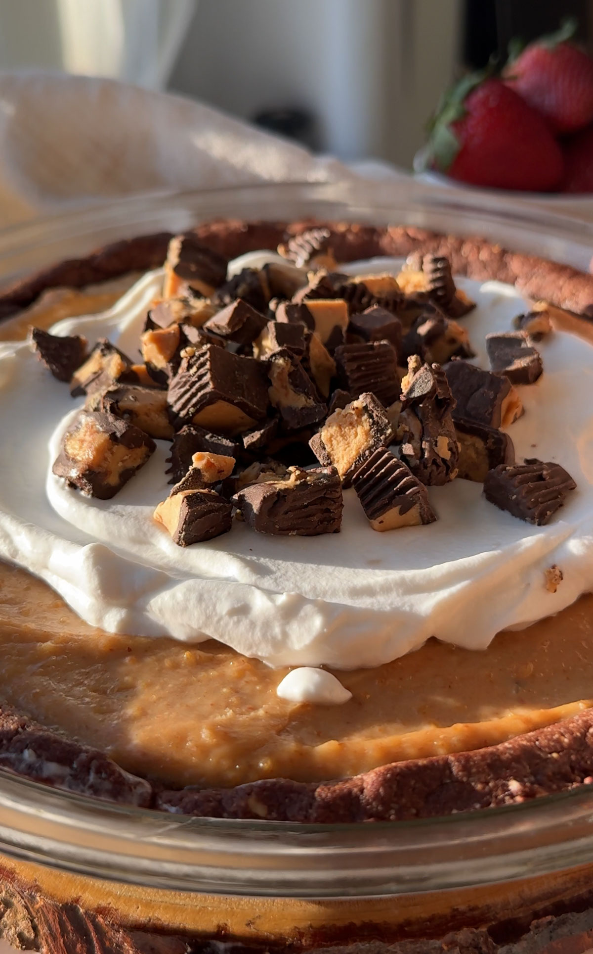 Vegan peanut butter pie in a pan topped with whipped cream and peanut butter cups. 