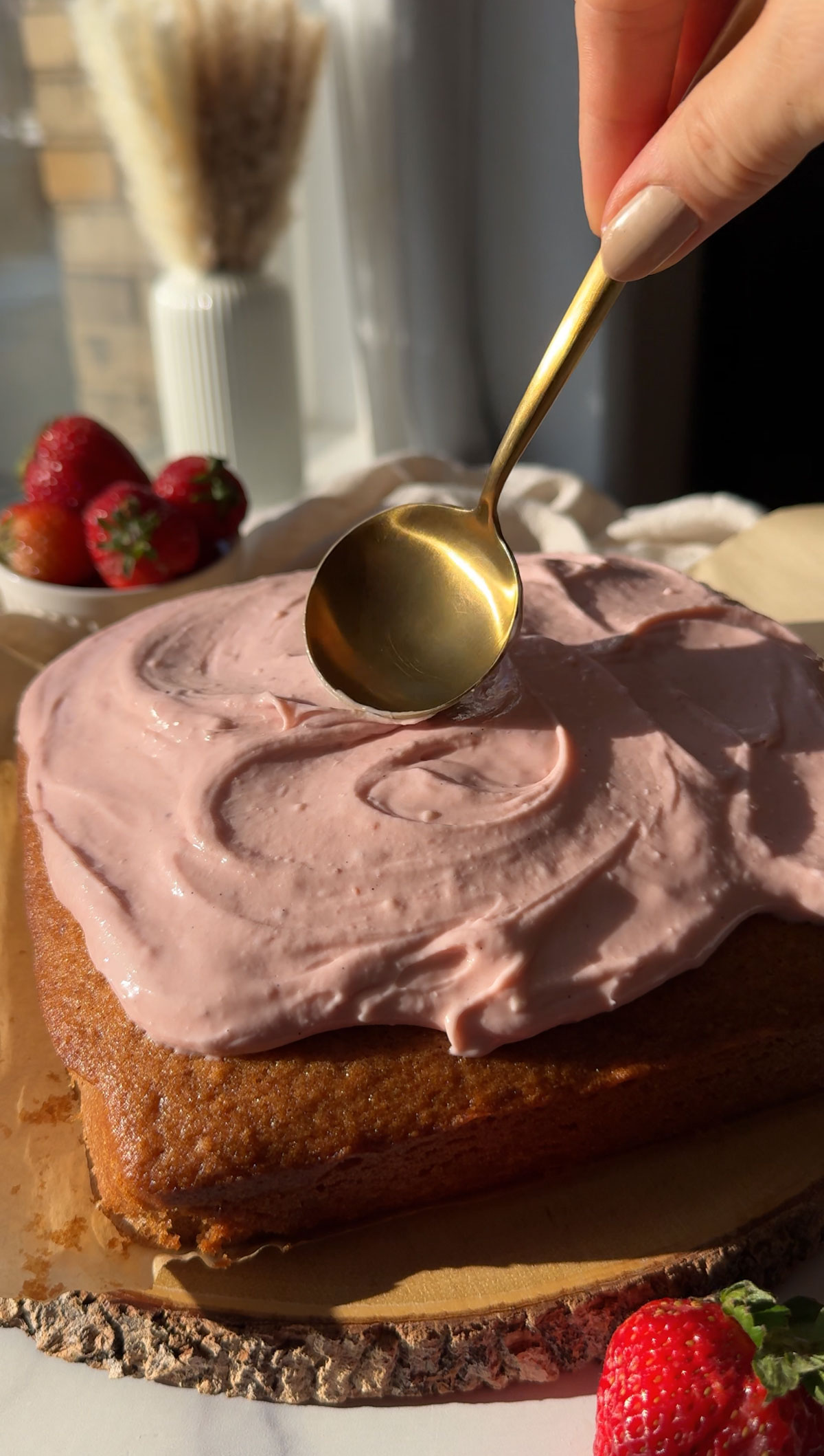 Adding pink frosting on a strawberry cake.