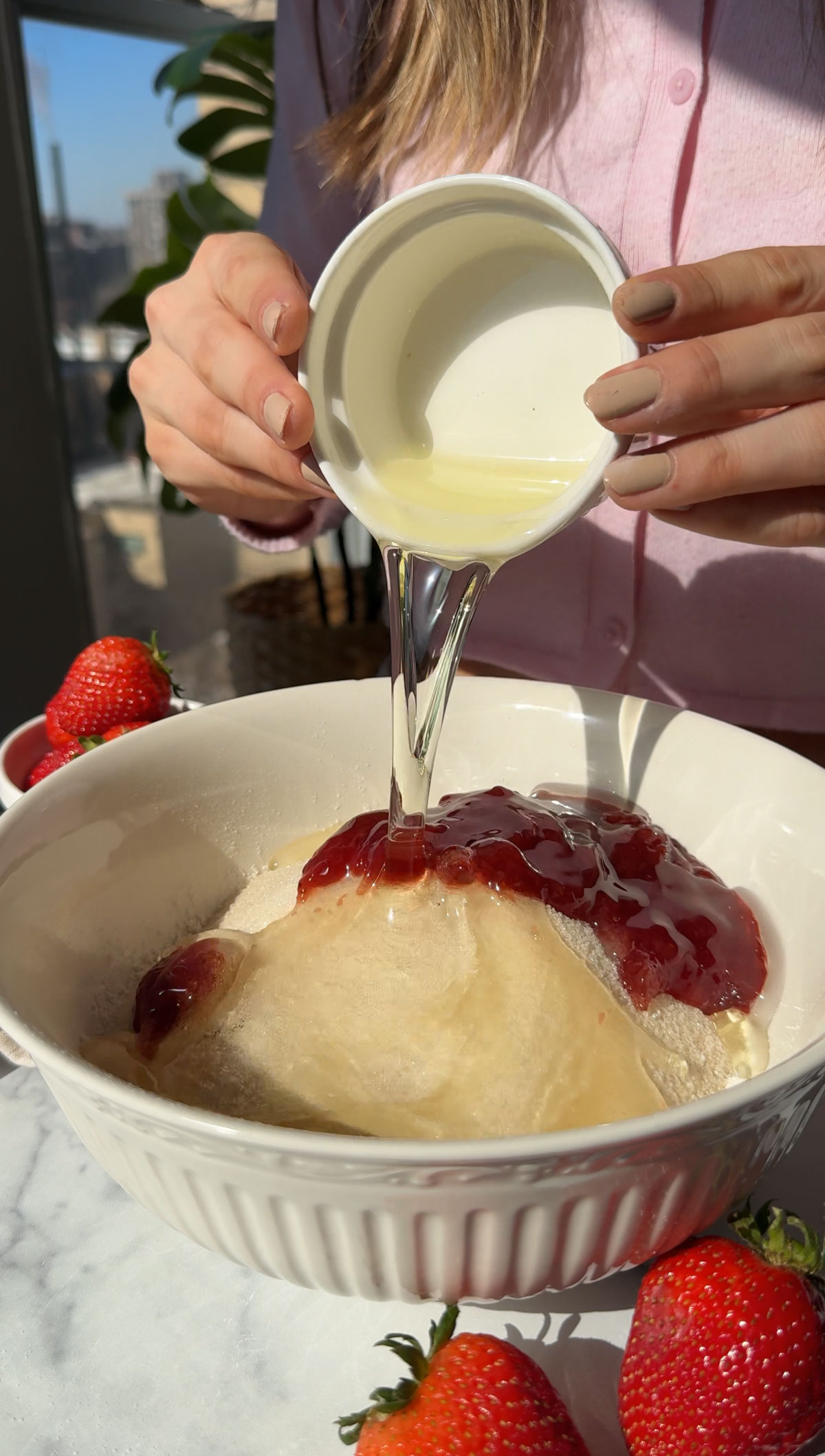 Adding all the ingredients to a bowl to make vegan strawberry cake batter.