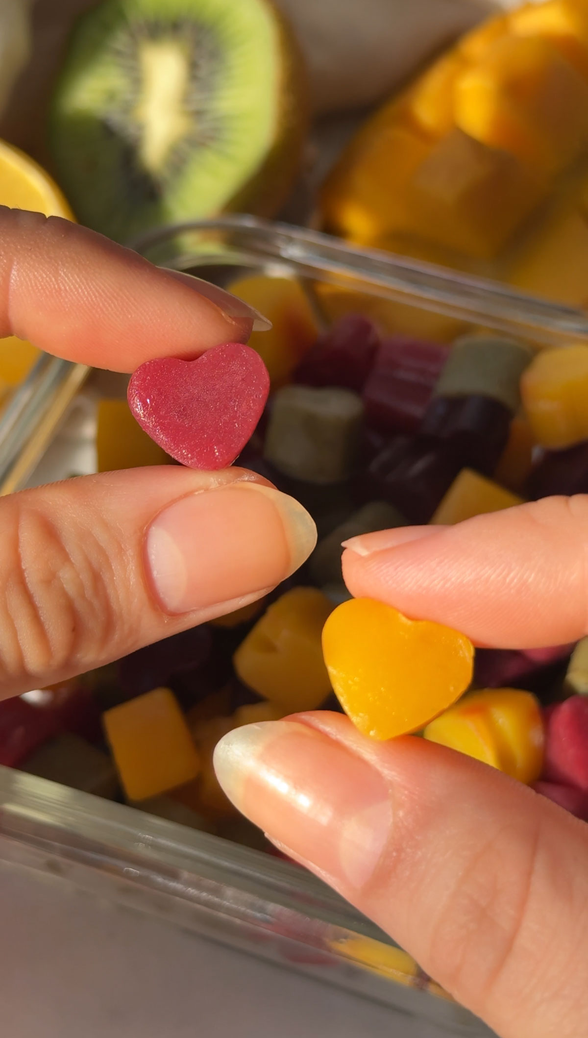 Hands holding up a red and yellow vegan gummy heart.