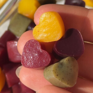 Vegan gummies in different colors and flavors held in a hand.