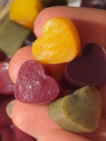Vegan gummies in different colors and flavors held in a hand.