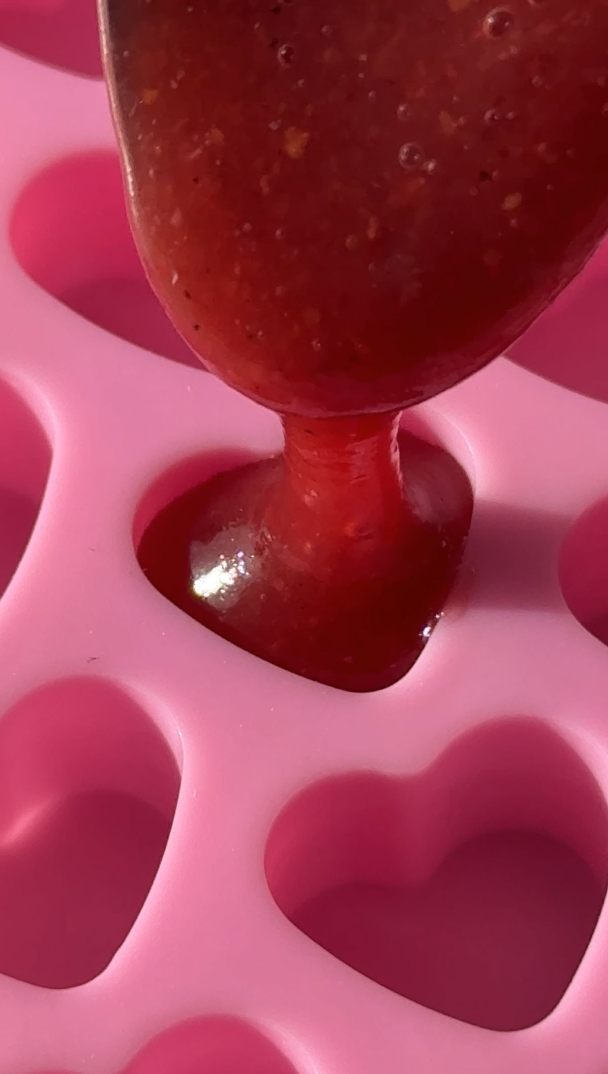 Adding the vegan gummy mixture to a hearty shaped mold. 