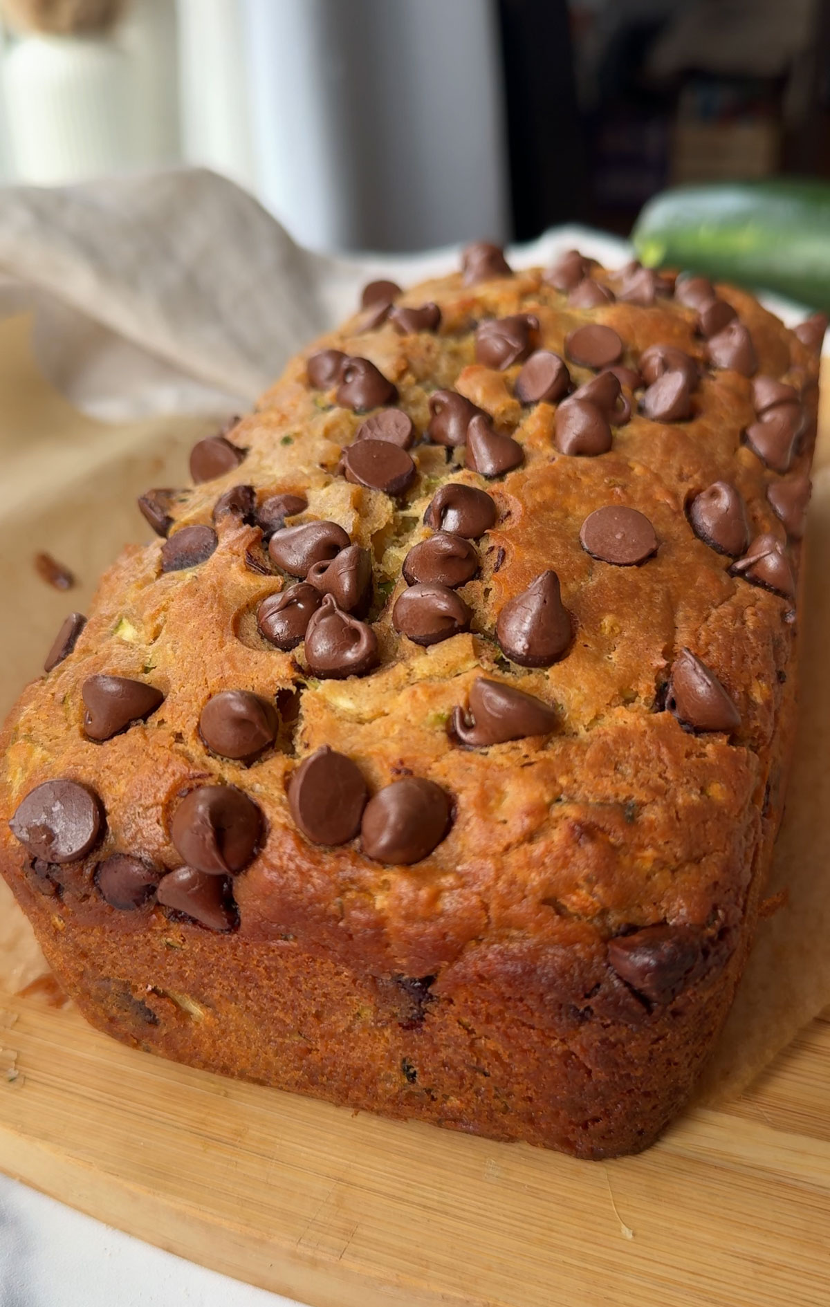 Baked vegan zuccchini bread cooling on a wooden cutting board.