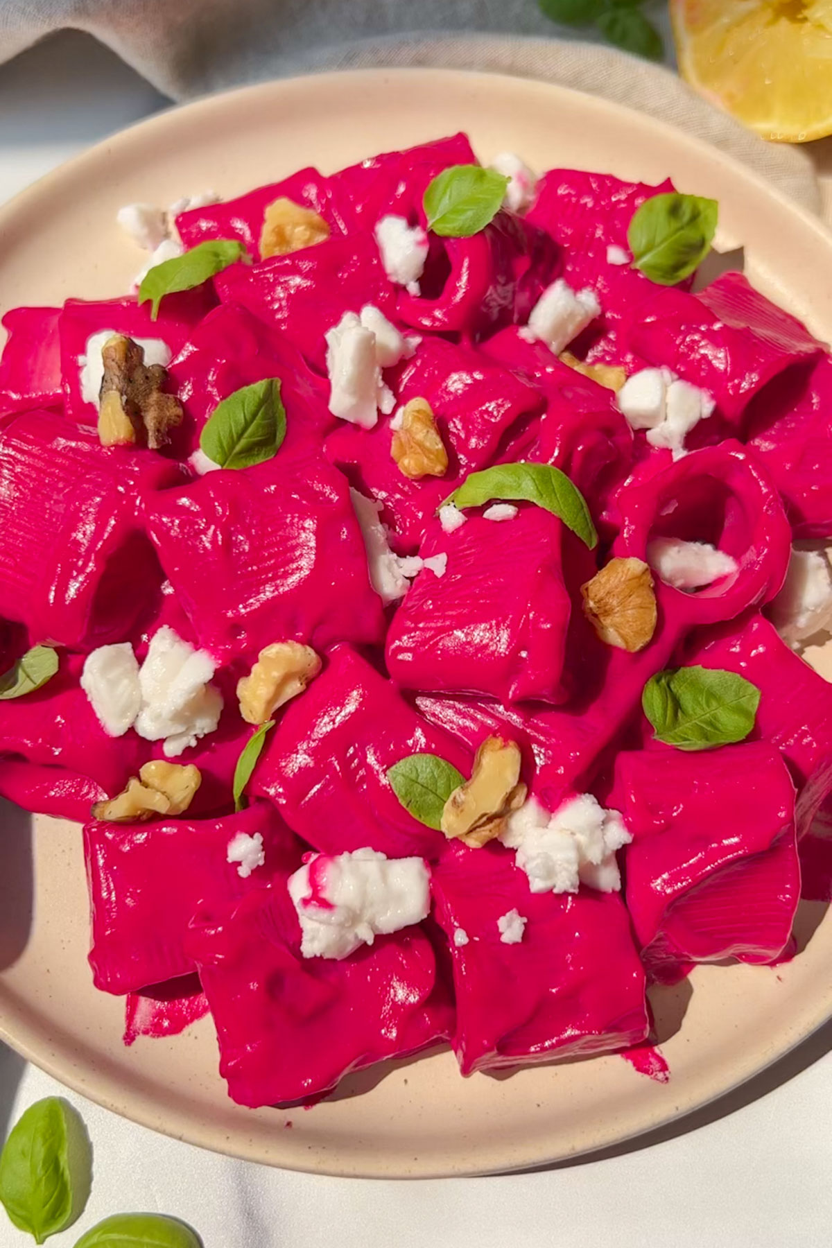 Beet pasta on a plate garnished with walnuts and basil.