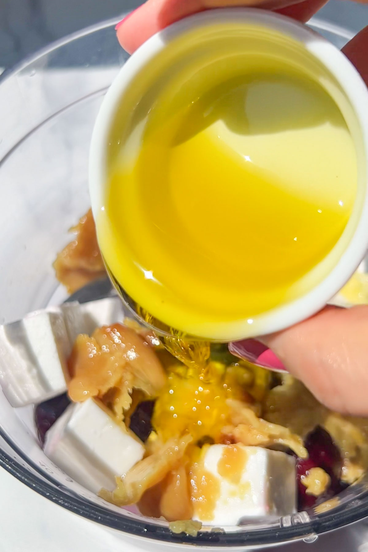 Olive oil being drizzled into a blender with the beets and other ingredients.