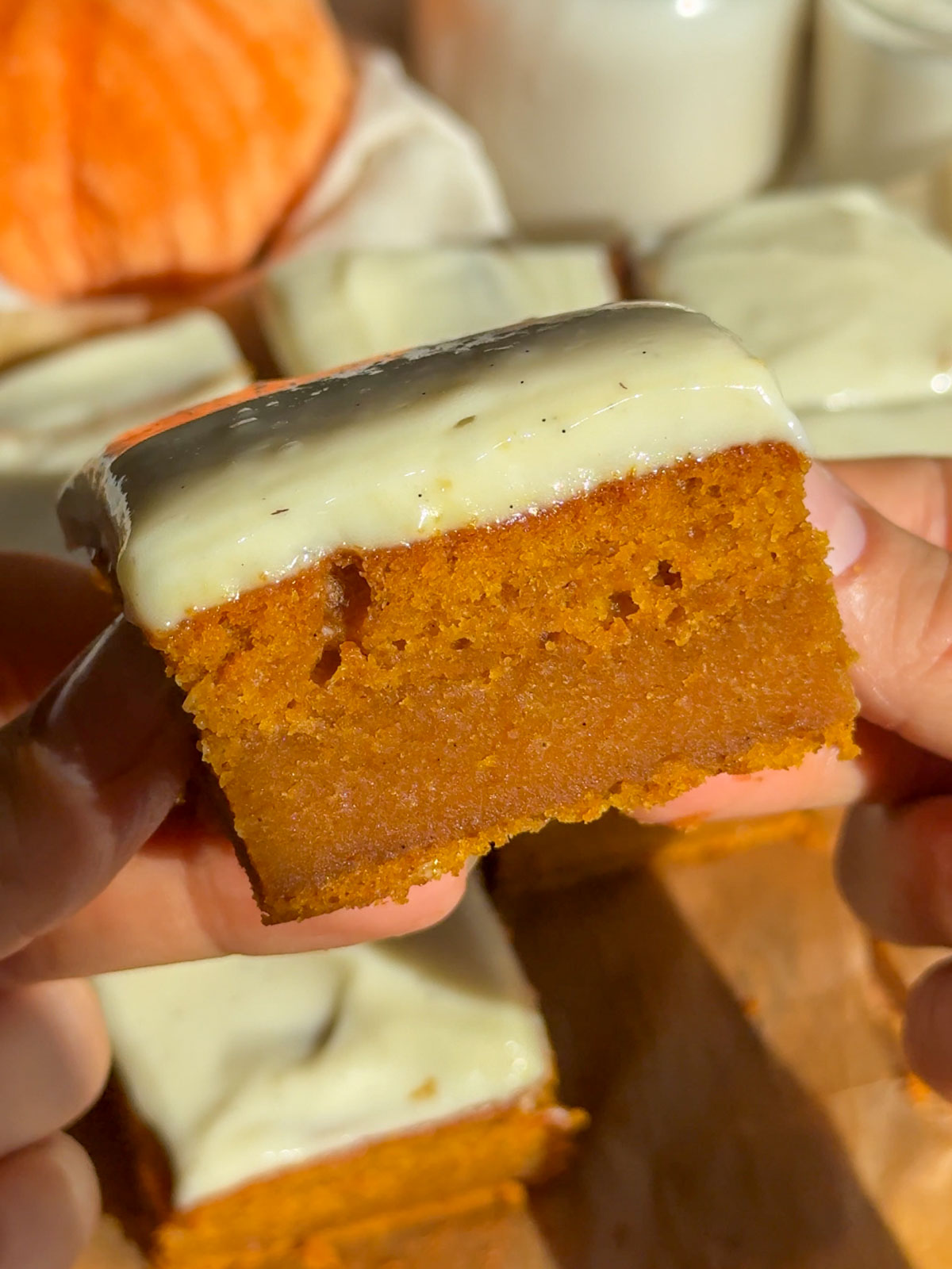A slice of pumpkin cake with cinnamon cream cheese frosting.